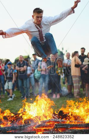 Kyiv, Ukraine - July 6, 2018: Young Man Jumps Over The Flames Of Bonfire During The Traditional Slav