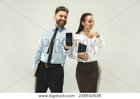 Happy Boss. Man And His Secretary Standing At Office Or Studio. Business Man Showing The Phone To Ca