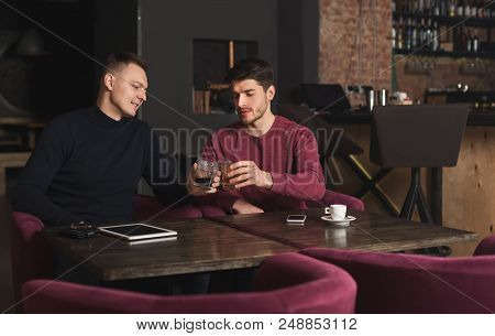 Friendly Talk In Bar. Top View Of Two Happy Young Men Talking To Each Other And Enjoying Whiskey, Cl