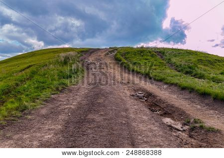 Ornate Dodgy Mountain Road With Green Grass On The Sides Leading To The Top Of The Mountain