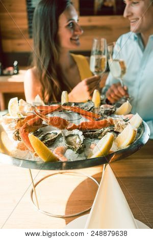 Close-up of fresh oysters and crabs served on ice with slices of lemon at the table of a romantic young couple eating at restaurant