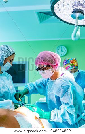 Cosmetic Liposuction Surgery In Actual Operating Room Setting Showing Surgeon Hands And Cannula