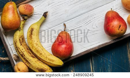 Fresh Fruit On A White Wooden Tray: Banatas, Pears, Apricots. Countryside Setting. Top View. Copy Sp