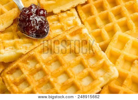Close-up Of Homemade Brown Waffles With Marmelade On A Spoon.
View To Stacked Wafles With Jam.
Baker