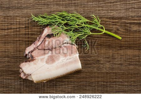 Group Of Three Slices Of English Bacon With One Sprig Of Dill Flatlay On Brown Wood