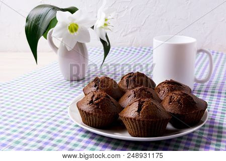 Chocolate Muffins, Coffee Mug And White Lily In Rustic Vase On The Green Purple Checkered Linen Napk