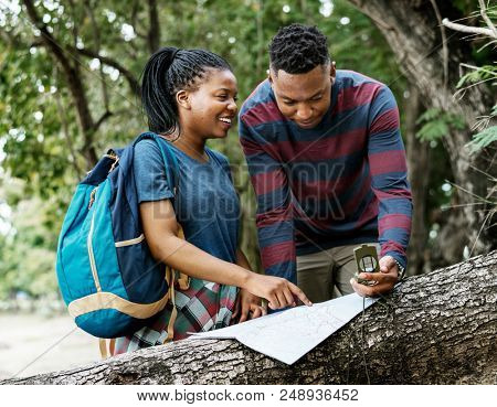Trekking couple using map and compass in a forest