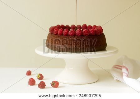 Chocolate Brownie Cake With Raspberries And Chocolate Icing On A Light Background. Selective Focus.
