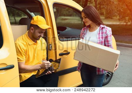 Delivery Guy Sittting In Side Of His Van With Client Next To Him. Gorgeous Woman Holding Big Tan Car