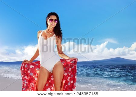 beautiful woman in a bathing suit derives pleasure on the beach during her holiday