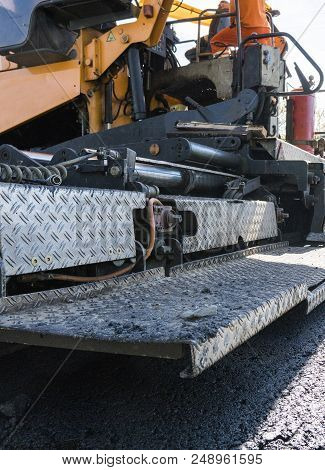 Worker Operating Asphalt Paver Machine During Road Construction And Repairing Works. A Paver Finishe