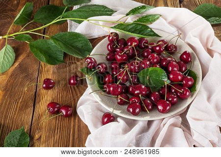 Large Ripe Cherries With Tails In Ceramic Dish, On Table With Light Cloth