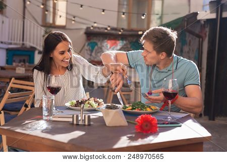 Lacking Manners. Dark-haired Laughing Woman Lacking Good Manners While Sitting In Restaurant