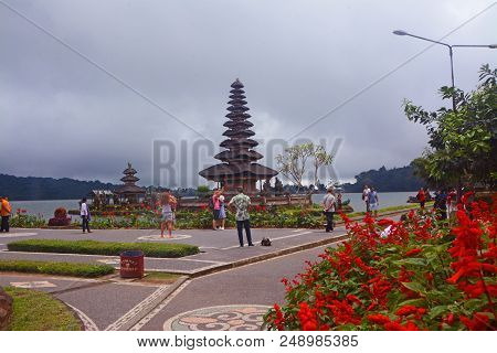 Bali - Indonesia. December 11, 2017. Red Flowers And Ulundanu Temple At Bedugul, Bali Island, Indone