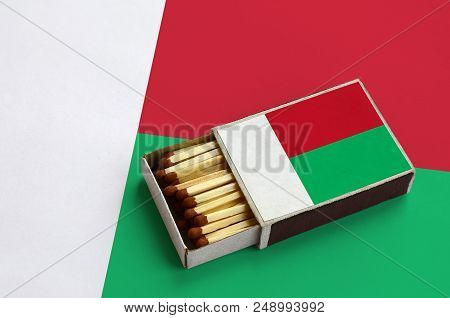Madagascar Flag  Is Shown In An Open Matchbox, Which Is Filled With Matches And Lies On A Large Flag