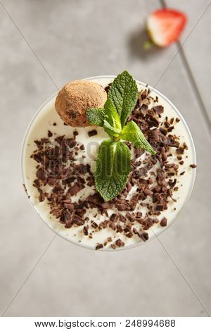 Chocolate Truffle Panna Cotta with Chocolate Flakes and Strawberry. Yummy Dessert Pannacotta in Elegant Tall Glass Decorated with Fresh Mint Leaves and Swiss Truffles. Close up Top View Dessert