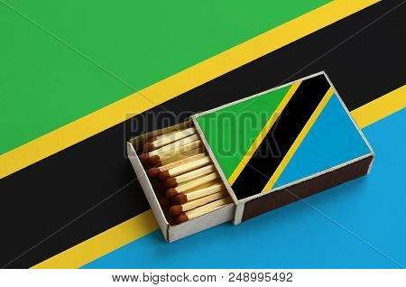 Tanzania Flag  Is Shown In An Open Matchbox, Which Is Filled With Matches And Lies On A Large Flag.