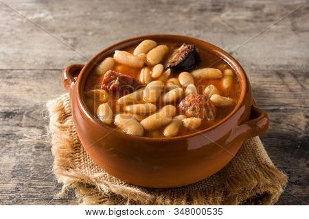 Typical Spanish Fabada Asturiana On Wooden Table