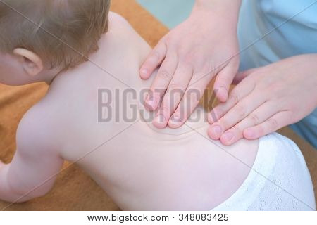 Professional Doctor Masseur Making Massage To Baby On Back In Clinic. Mom Playing Toy With Baby. The
