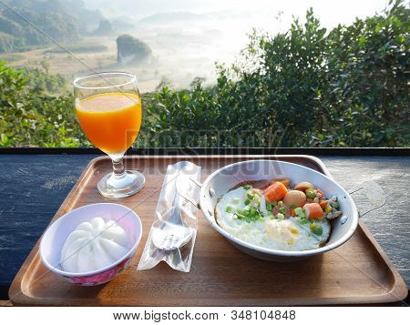 Breakfast With Mountain View. Pan-fried Egg With Sausage Topping, Chinese Steamed Bun And Orange Jui