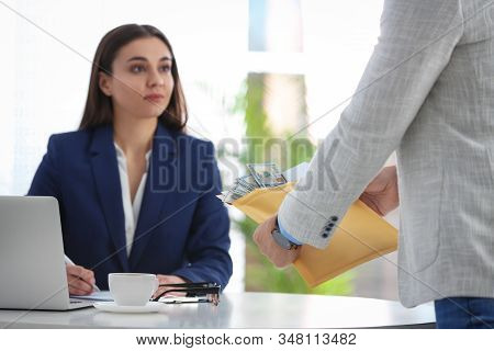 Man Offering Bribe To Businesswoman At Table In Office