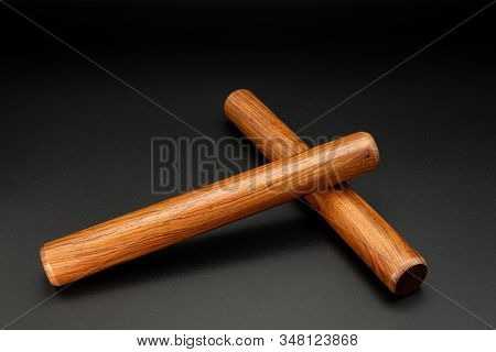 Closeup Of A Pair Of Wooden Claves Lying On A Black Underground