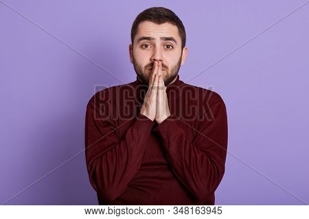 Close Up Portrait Of Bearded Handsome Man With Hopeful Facial Expression Putting Hands Together, Wea