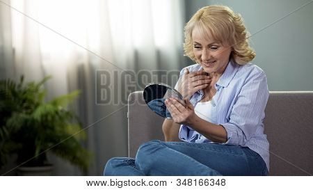 Mature Woman Looking Into A Hand Mirror, Enjoying Reflection, Anti-age Cosmetics