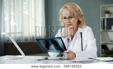 Concerned Female Pulmonologist Examining X-ray Of Patient's Lungs, Diagnostics