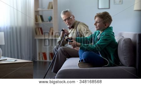 Dissatisfied Grandpa Looking At Happy Grandson Playing Video Game Generation Gap