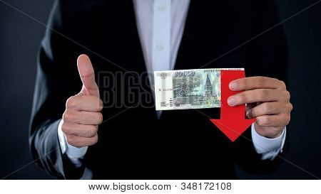 Businessman Holding Russian Ruble Banknotes Showing Thumbs Up, Arrow Falling