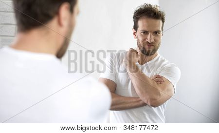 Self-affected Macho Looking In Mirror At His Muscles And Biceps After Workout