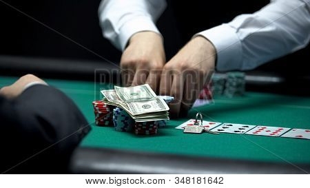 Confident Croupier Matching Bet Of Casino Client Going All-in With Money And Key