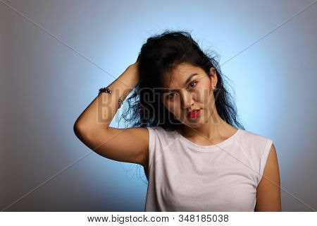 Asian Model With A Cryptic And Insightful Look On A Background With Blue Highlight. Studio Portrait 