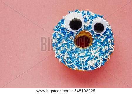 Vanilla Dip Donut With Black Wiggle Googly Eyeballs On A Coloured Blue And White Sprinkles On A Pink