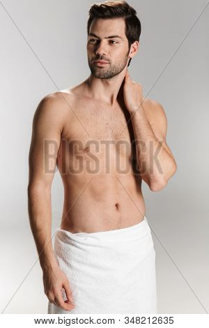 Photo of athletic half-naked man in bath towel posing and looking aside isolated over white background