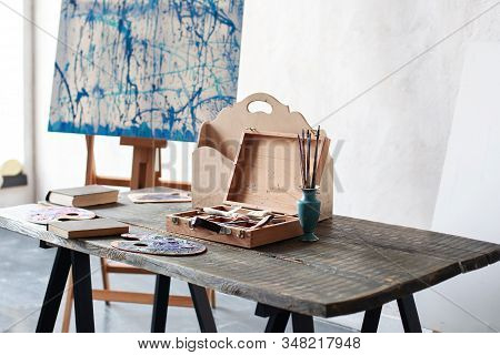 Workplace Of The Artist. Artwork Tools On A Wooden Table. Education Concept. Clutter In Artist Works
