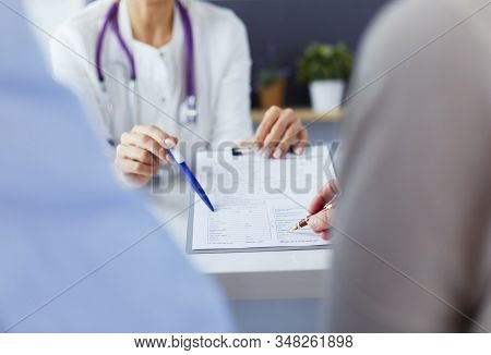 Doctor And Patient Examining A File With Medical Records, She Is Sitting On A Wheelchair