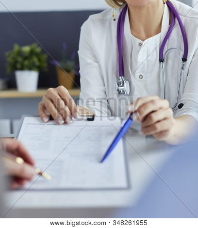 Doctor And Patient Examining A File With Medical Records, She Is Sitting On A Wheelchair