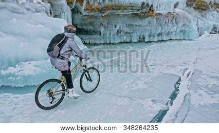 Woman Is Riding Bicycle Near The Ice Grotto. The Rock With Ice C