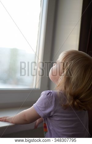 A Little Girl Standing In Front Of A Window