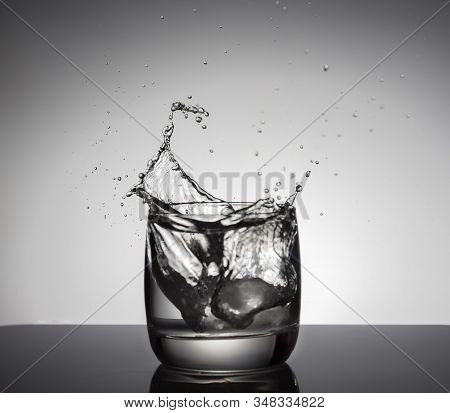 Ice Cubes Splashing Into Glass Of Water.