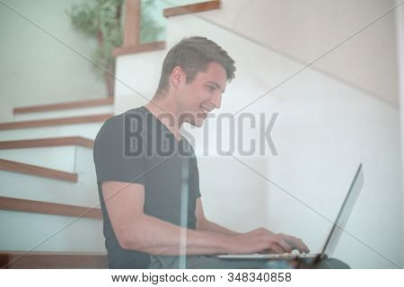 casual young man working on laptop in his apartment