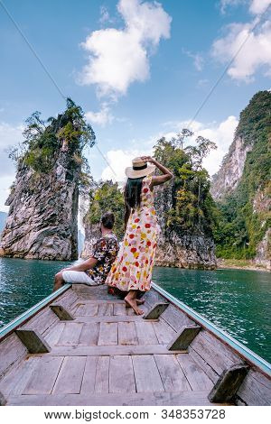 Couple Traveling By Boat Exploring Epic Limestone Cliffs In Huge Lake In Khao Sok National Park, Chi
