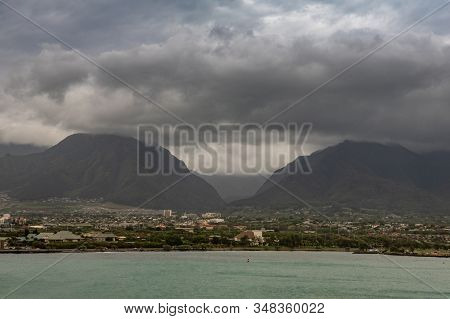 Kahului, Maui,, Hawaii, Usa. - January 13, 2020: 2 Black Mountains Tower Over Cityscape Under Heavy 