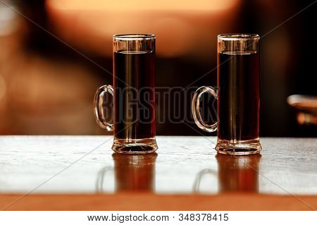 Two Glasses Of Alcoholic Shots On The Bar. Mini Cocktail Shooters Over Wooden Background.
