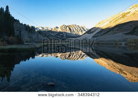 Bright Blue Still Lake Surface Reflectiong Surrounding Mountain
