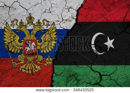Flag Of Russia And Libya On Textured Cracked Earth. The Concept Of Cooperation Between The Two Count