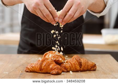 Baker Sprinkles Croissants With Almond Flakes. Delicious Viennoiserie