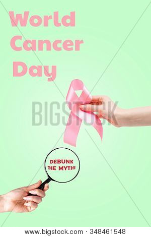 World Cancer Day. Womens Hand With A Pink Ribbon And A Magnifying Glass On A Light Green Background.